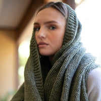 A woman with a dark green organic cotton throw wrapped around her head.