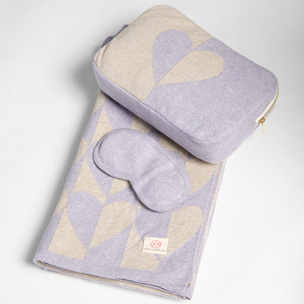 Set of lavender eye mask, blanket and pouch with heart design on a light gray background.