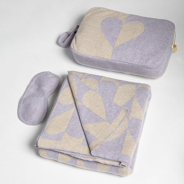 Set of gray and lavender patterned blanket with a matching heart pouch and eye mask on a light gray background.