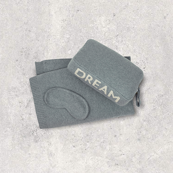 Gray cotton eye mask and compact pouch with 'DREAM' text on a light gray background.
