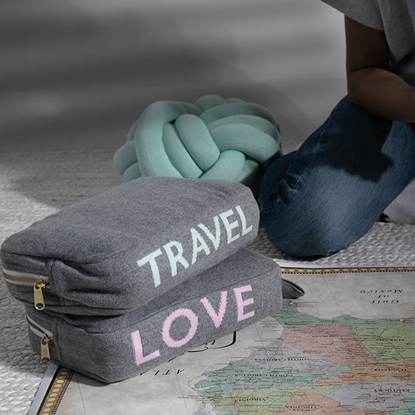 Two medium gray travel pouches with 'TRAVEL' and 'LOVE' text on top of a map.