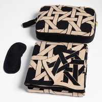 Black and beige patterned travel set with pouch and eye mask on a white background