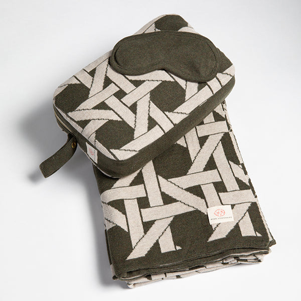 Soft olive green organic cotton travel blanket with a geometric design, paired with a mask and bag. Ideal for airplane travel.