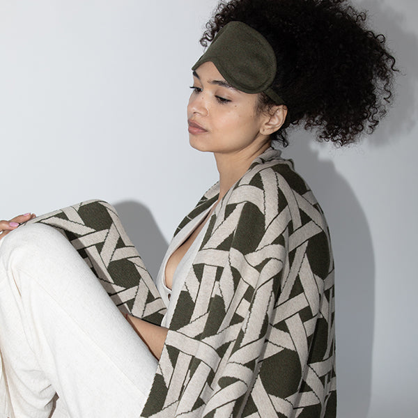 Woman wrapped in the riti green patterned cotton blanket and green eye mask.