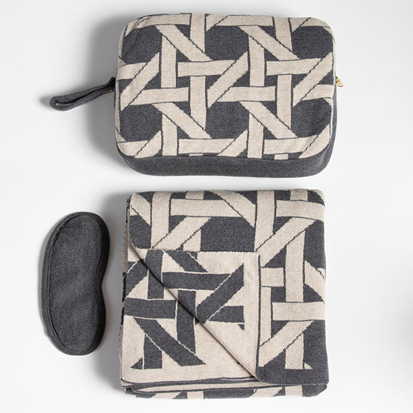 Soft grey organic cotton travel blanket with a geometric design, paired with a mask and pouch. Ideal for airplane travel.