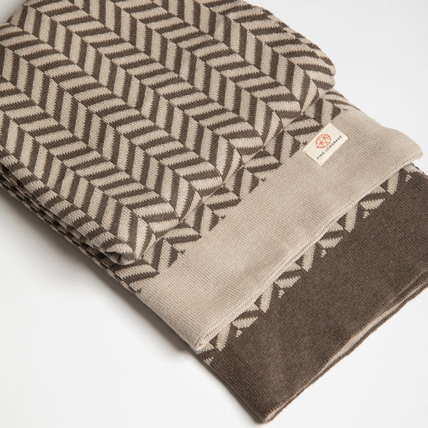 Folded organic cotton throw with brown chevron pattern on a white background.